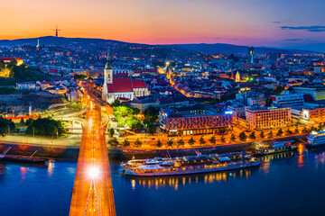 Fototapeta premium Bratislava, Slovakia - June 2022: City skyline on the shores of the Danube river; Bratislava castle, the old town, Eurovea; UFO bridge; SNP bridge; Apollo Bridge