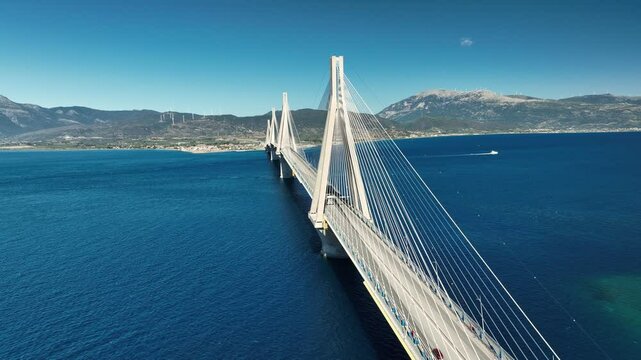 Aerial view of Rion-Antirion Bridge in Patras, suspension bridge stretching across the blue waters of the Gulf of Corinth, connecting the Peloponnese to mainland Greece, surrounded by mountains 