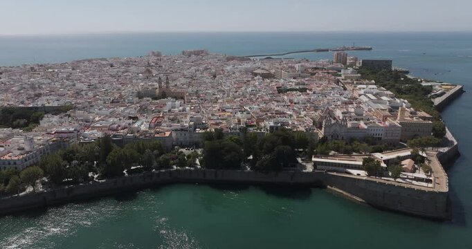 Aerial drone wide cityscape of C&aacute;diz in Spain, Andalusia, Europe, on bright sunny day, facing San Sebastian castle fortress and lighthouse and Baluarte de la Candelaria. Shot in 5K ProRes 422 HQ