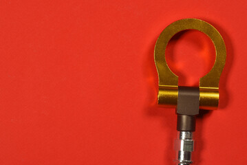 Sport car tow hook on the red flat lay background close up with copy space.