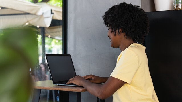 Side view of young woman using laptop at cafe, she is working on laptop computer at a coffee shop.