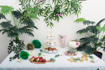 Obraz premium Sweet holiday table with tasty cupcakes with cream with green plants decoration