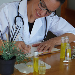 homeopathic woman writing in a notebook surrounded by jars of oils, herbs, and seeds