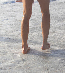 A woman's legs are wet and she is standing on a beach