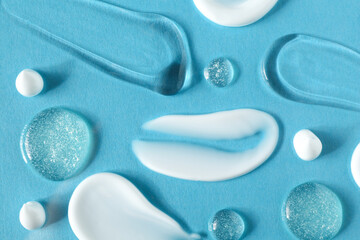Smears of different cosmetic products on light blue background, flat lay
