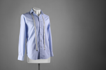Male mannequin with light blue shirt and measuring tape on grey background, space for text © New Africa