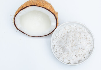 Half cut mature coconut fruit with its flakes in ceramic bowl on white background
