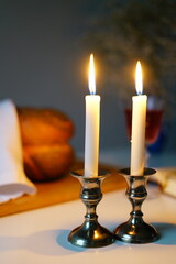 Shabbat or Sabbath kiddush ceremony composition with a traditional sweet fresh loaf of challah bread, glass of red kosher wine and candles on a vintage wood table with copy space