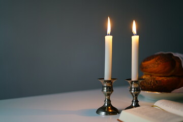 Shabbat or Sabbath kiddush ceremony composition with a traditional sweet fresh loaf of challah bread, glass of red kosher wine and candles on a vintage wood table with copy space
