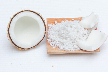 Grated coconut set on wooden board with half cut and pieces of coconut fruit