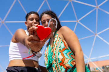 Lesbian couple holding a heart-shaped lock outdoors