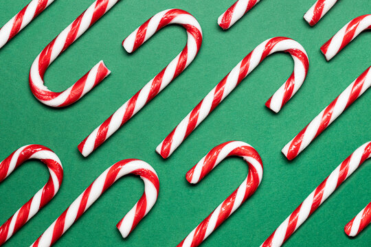 Top view of red and white candy canes on a green surface
