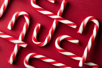 Top view of scattered candy canes on red background
