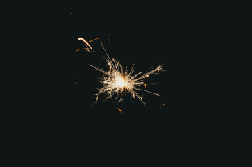 Fototapeta premium Sparklers sparkle brightly against a black background, creating the effect of magic and celebration, filling the atmosphere with joy
