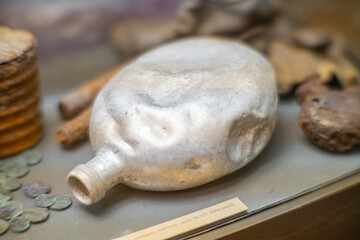 An old soldier's aluminum flask on a wooden table. Thermos for water. An empty flask with the stopper unscrewed.