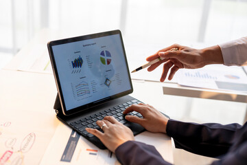A person is typing on a laptop with a picture of a pie chart on the screen