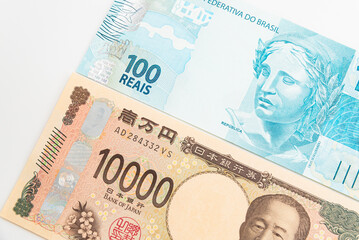 Close up of 10 thousand Japanese yen and one hundred Brazilian reais isolated on white background