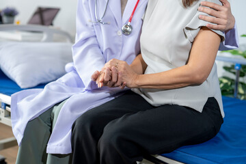 Obraz premium Doctor comforting patient by holding her hand in hospital room