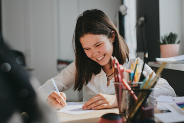Schoolgirl at home schooling. The girl sits at the table with textbooks doing homework