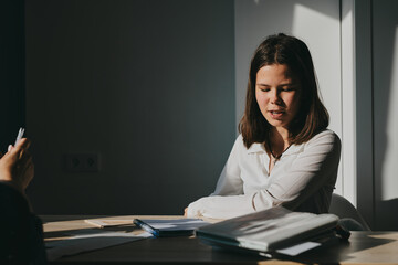 Schoolgirl at home schooling. The girl sits at the table with textbooks doing homework