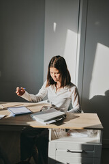 Schoolgirl at home schooling. The girl sits at the table with textbooks doing homework