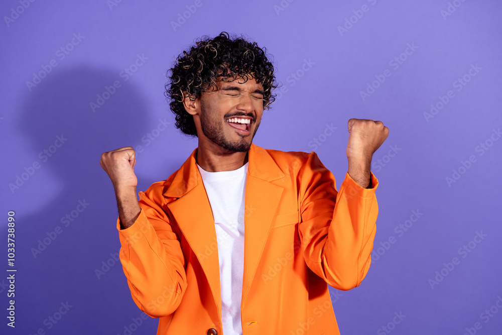 Wall mural Photo of lucky good mood guy wear orange suit rising fists emtpy space isolated violet color background