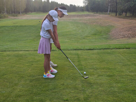 Two young girls practicing their golf swings on a beautiful course during a sunny afternoon - Powered by Adobe