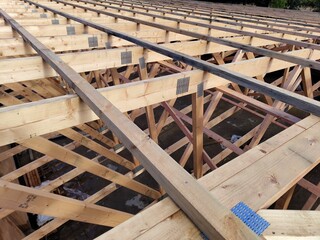 Overhead view of wooden trusses and beams in a large-scale construction project, featuring metal connector plates for structural integrity