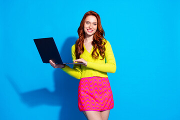 Photo portrait of pretty young girl hold netbook wear trendy yellow outfit isolated on blue color background