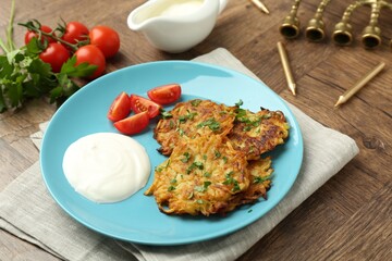Delicious potato pancakes, menorah and candles on wooden table, closeup. Hanukkah festive food