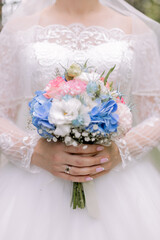 the bride in a white dress holds a wedding bouquet at the wedding