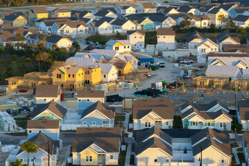 Aerial view of unfinished wooden frames of affordable houses under construction. Development of...