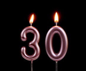 Burning pink birthday candles isolated on black background, number 30