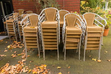Stacked chairs waiting for the return of customers in front of a restaurant in autumn