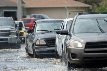 Flooded street after hurricane rainfall with driving cars in Florida residential area. Consequences...