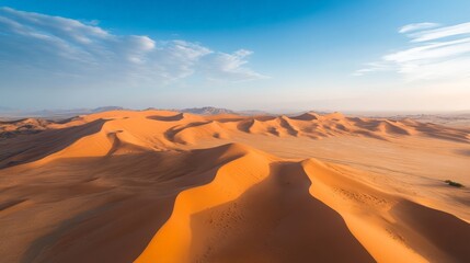 Fototapeta premium A breathtaking drone shot of a desert landscape, with towering sand dunes casting long shadows under the late afternoon sun.