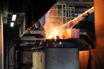 Molten metal pouring into containers in an industrial foundry. High-temperature manufacturing...
