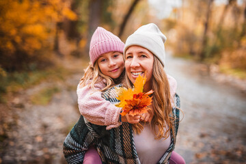 Joyful mom and his little child girl. mother and child have fun outdoors at autumn park.