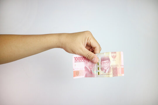 Hands giving out one hundred thousand money on white background, rupiah money 100000