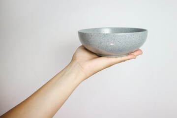 Hand holding an empty bowl isolated on white background