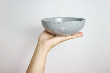 Hand holding an empty bowl isolated on grey background