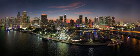 High illuminated skyscrapers of Brickell, city's financial center. Skyviews Miami Observation Wheel at Bayside Marketplace with reflections in Biscayne Bay water and US urban landscape at night