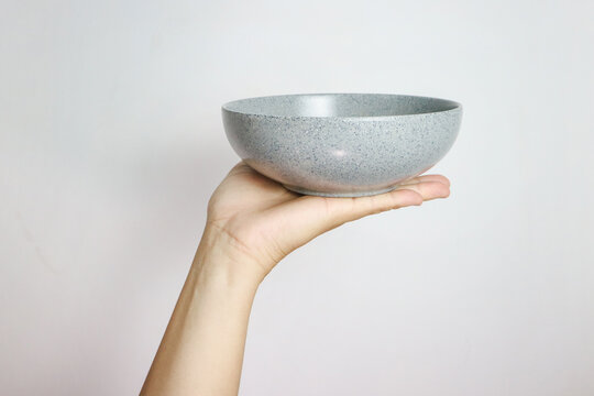 Hand holding an empty bowl isolated on grey background