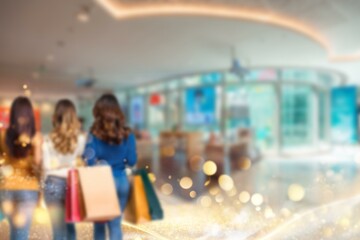 Blurry shot of three women in a shopping mall in China, holding bags after a shopping spree.