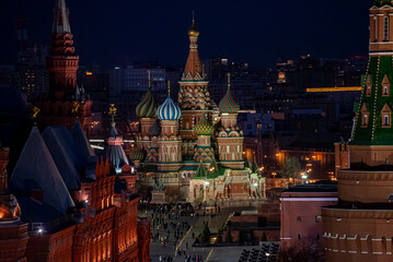 Top view of St. Basil's Cathedral in Moscow at night, with its vibrant domes illuminated, surrounded by historic buildings and the Kremlin towers under a on a spring evening, Russia