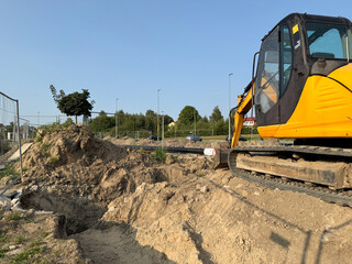 A yellow excavator moving dirt at a construction site on a clear day