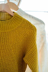 Warm cozy clothes on hangers. Knitted autumn sweaters. Home organization.