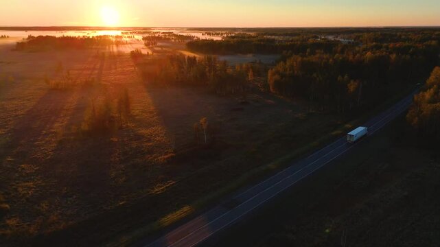A truck is driving along the road at sunset