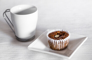 Close Up of a Hot Cup of Coffee or Tea with a Delicious Chocolate Muffin with Nut Slices on a White...