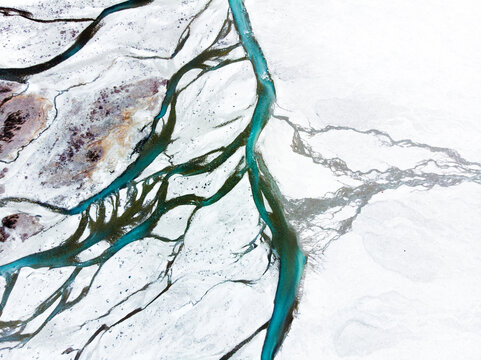 An aerial view of winding streams and river channels cutting through a barren landscape.